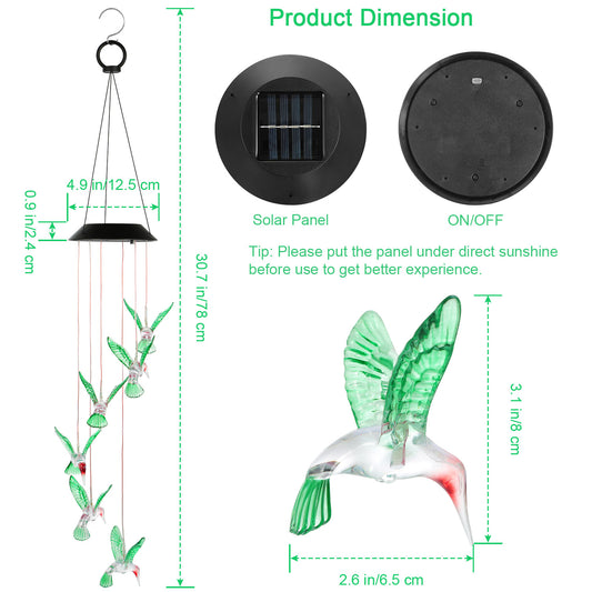 Hummingbird solar wind chime hanging from a garden tree branch at dusk